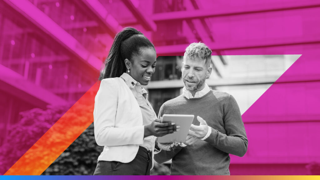 Two people looking at a tablet and smiling to promote the cdp vs crm article